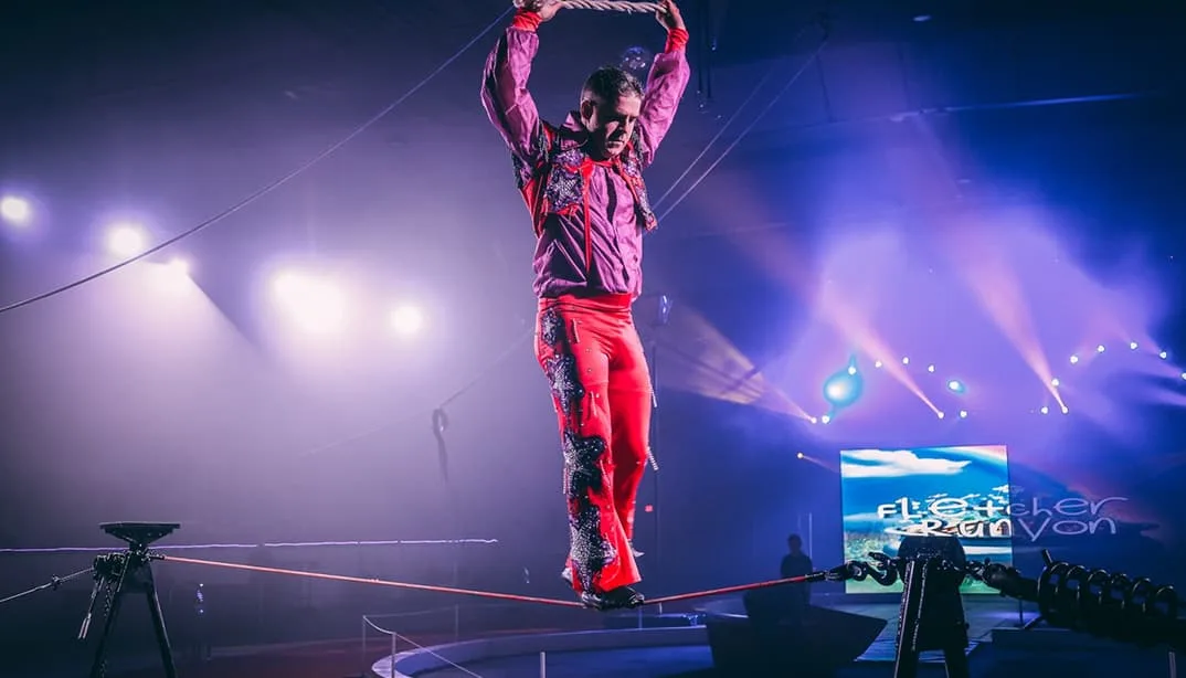 Performer walking tightrope under stage lights
